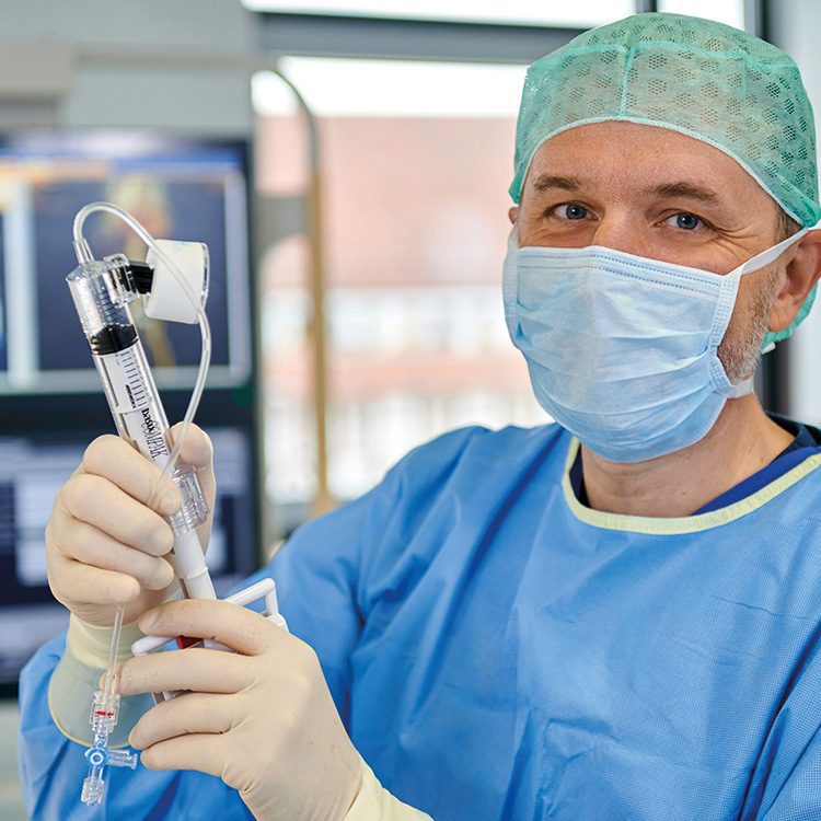 männliche Personen in blauer OP-Arbeitskleidung mit Mundschutz und Haube