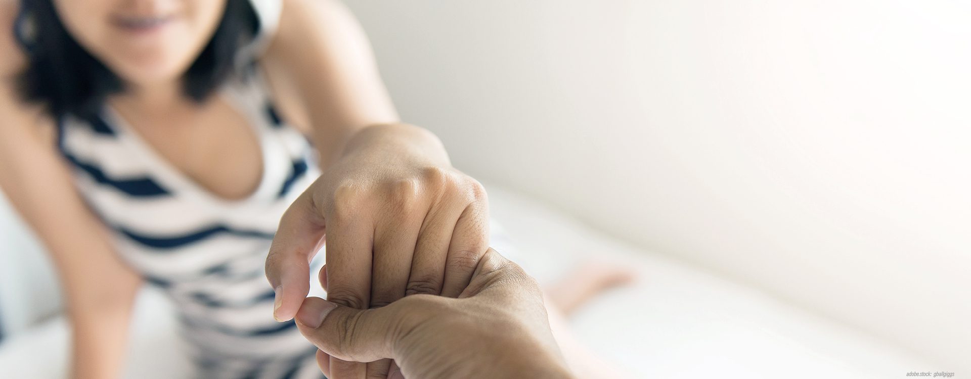 Frau reicht ihre Hand einer anderen, nicht erkennbaren Person, die diese ergreift