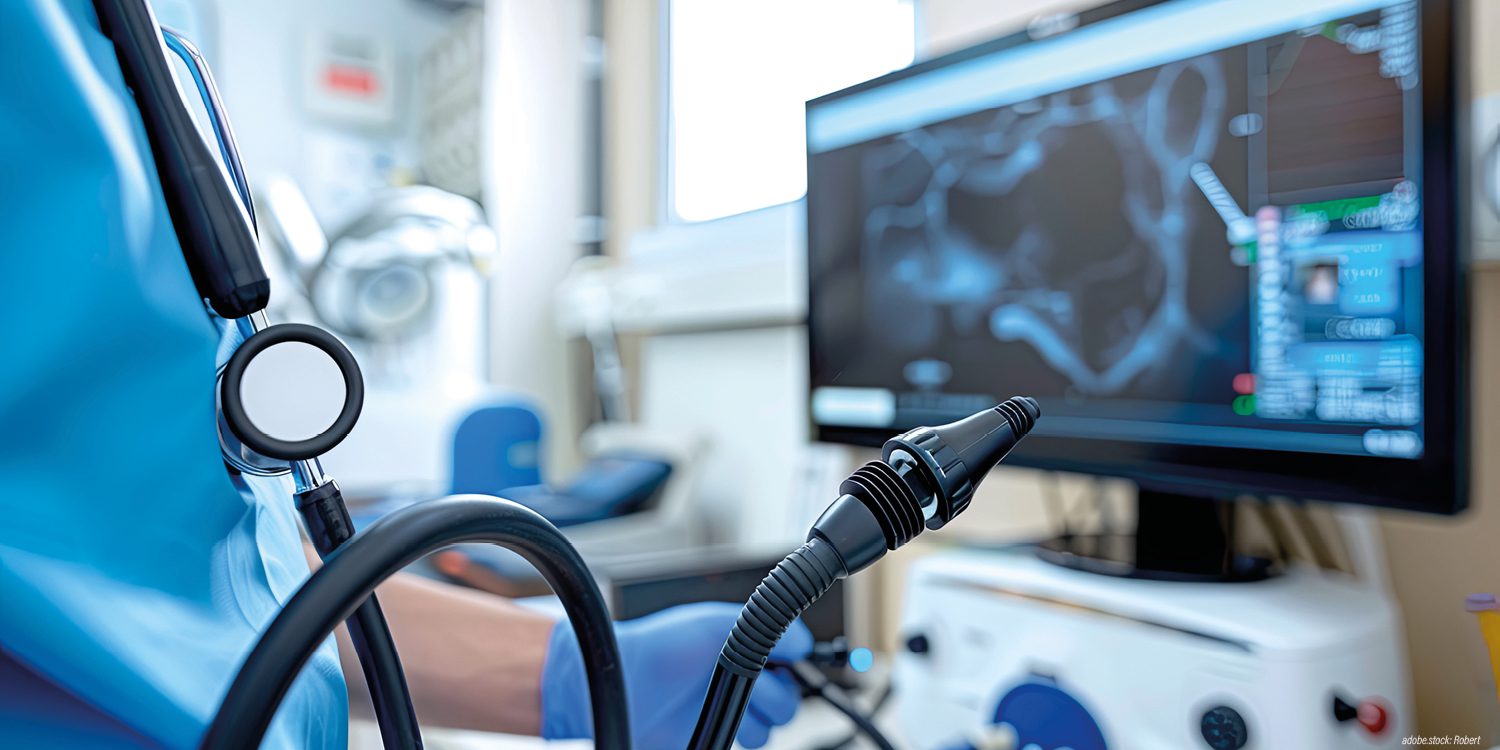 Person in bleuer Krankenhausarbeitskleidung mit Gastroskop betrachtet ein Bild am Monitor