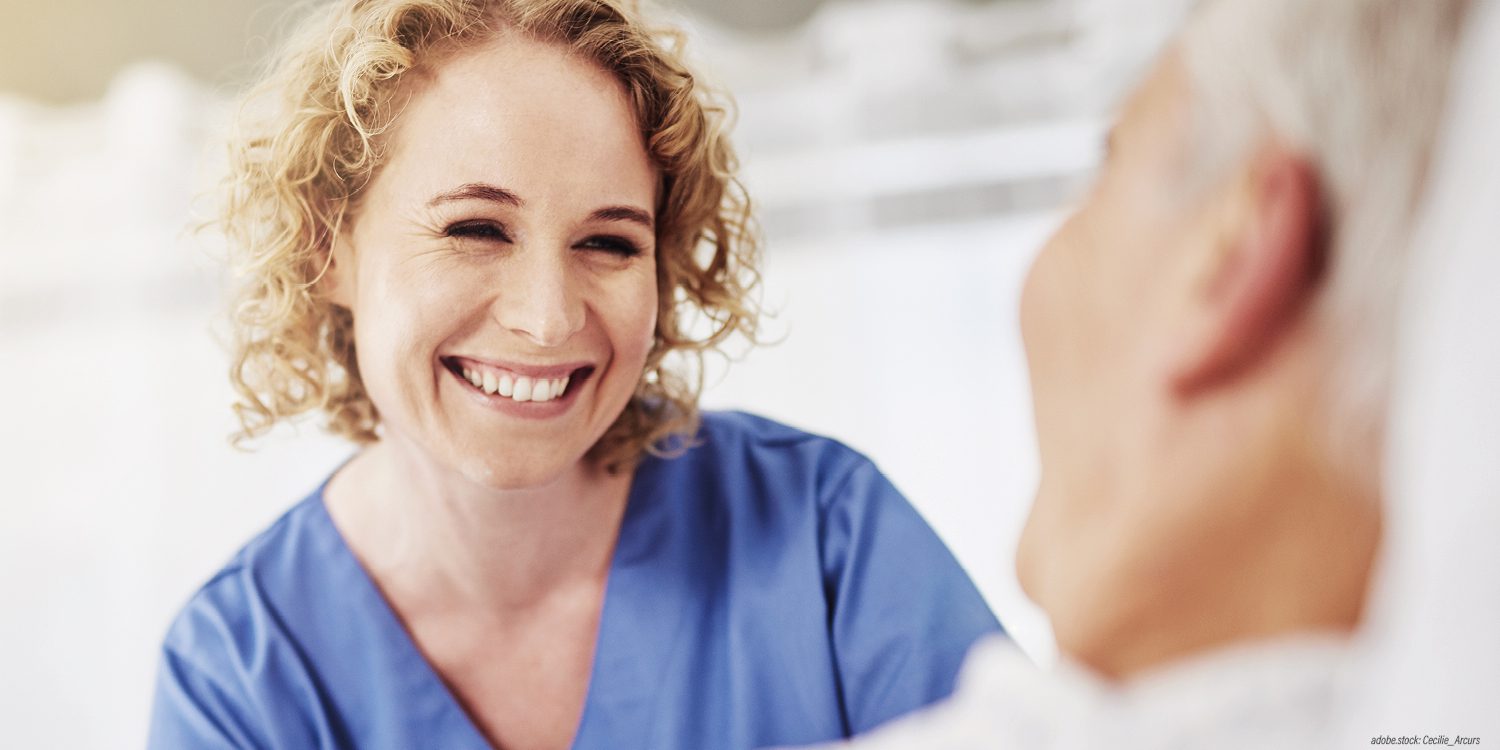 lächelnde weibliche Pflegekraft am Bett einer Patientin