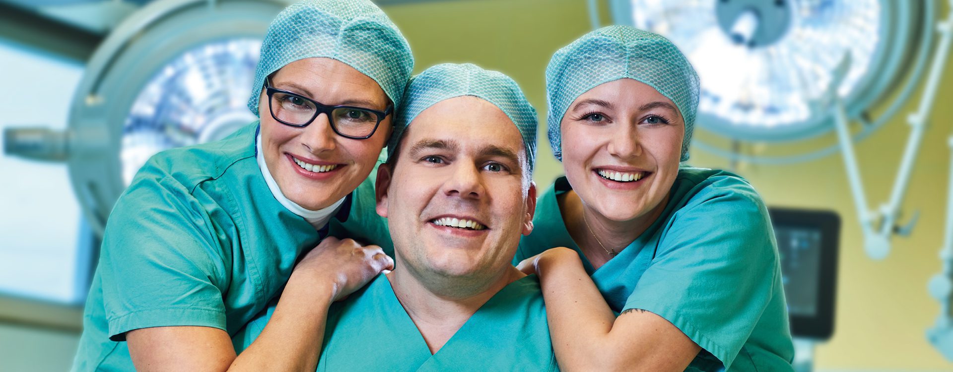 Ausschnitt von drei lächelnden Personen in grüner OP-Krankenhausarbeitskleidung im OP