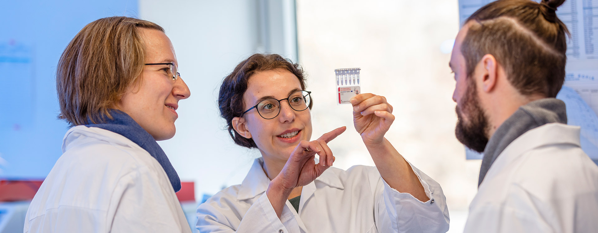 Laboranten in weißer Arbeitskleidung im Gespräch über eine Laborprobe