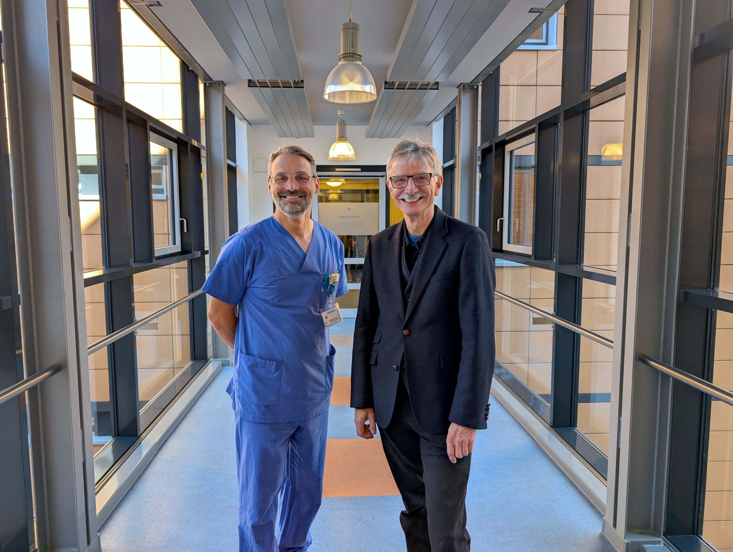 Prof. Dr. Gunnar Elke steht neben Prof. von Knobelsdorff in einem Gang mit Fenstern.